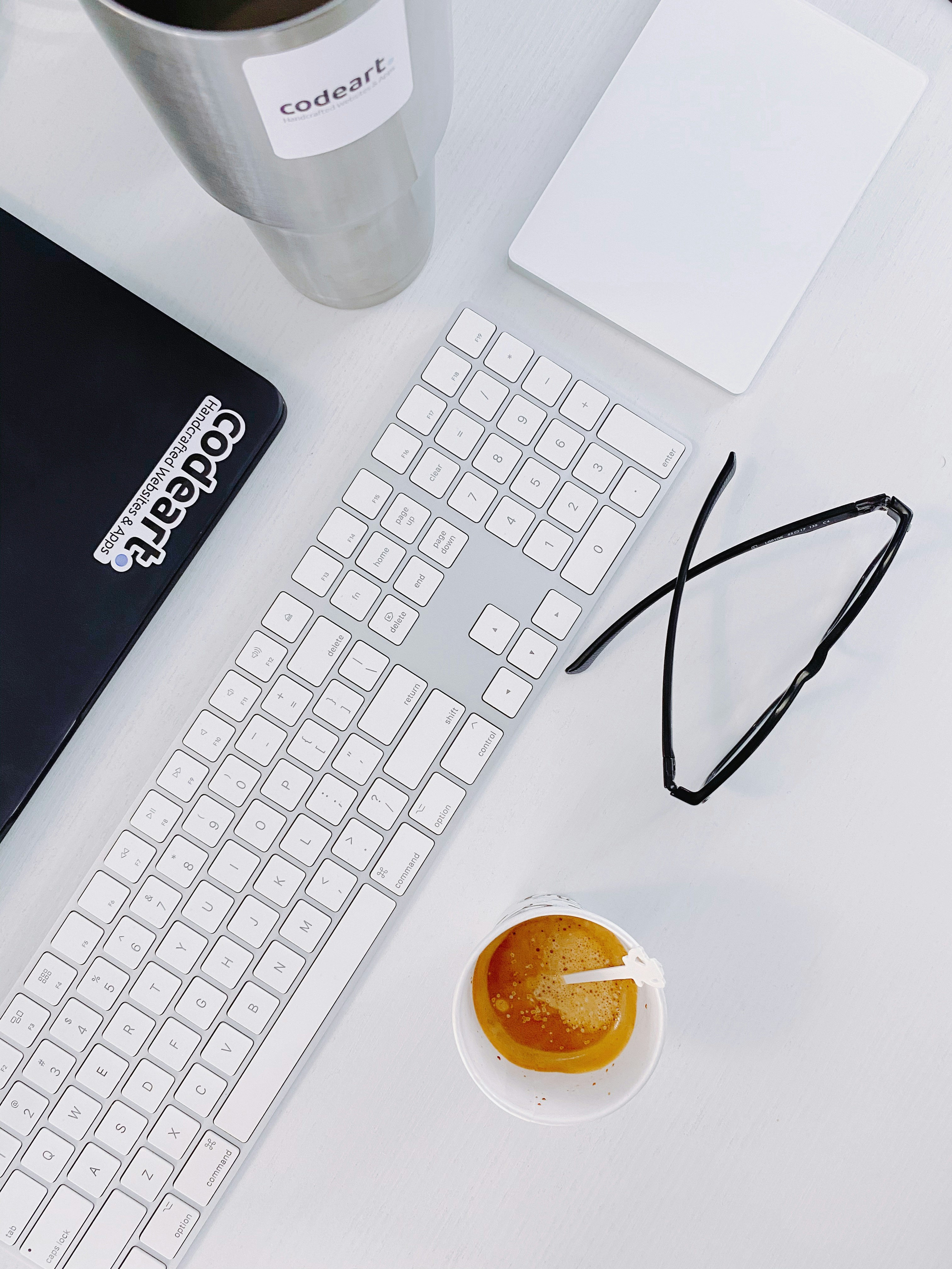 black framed eyeglasses beside white apple keyboard